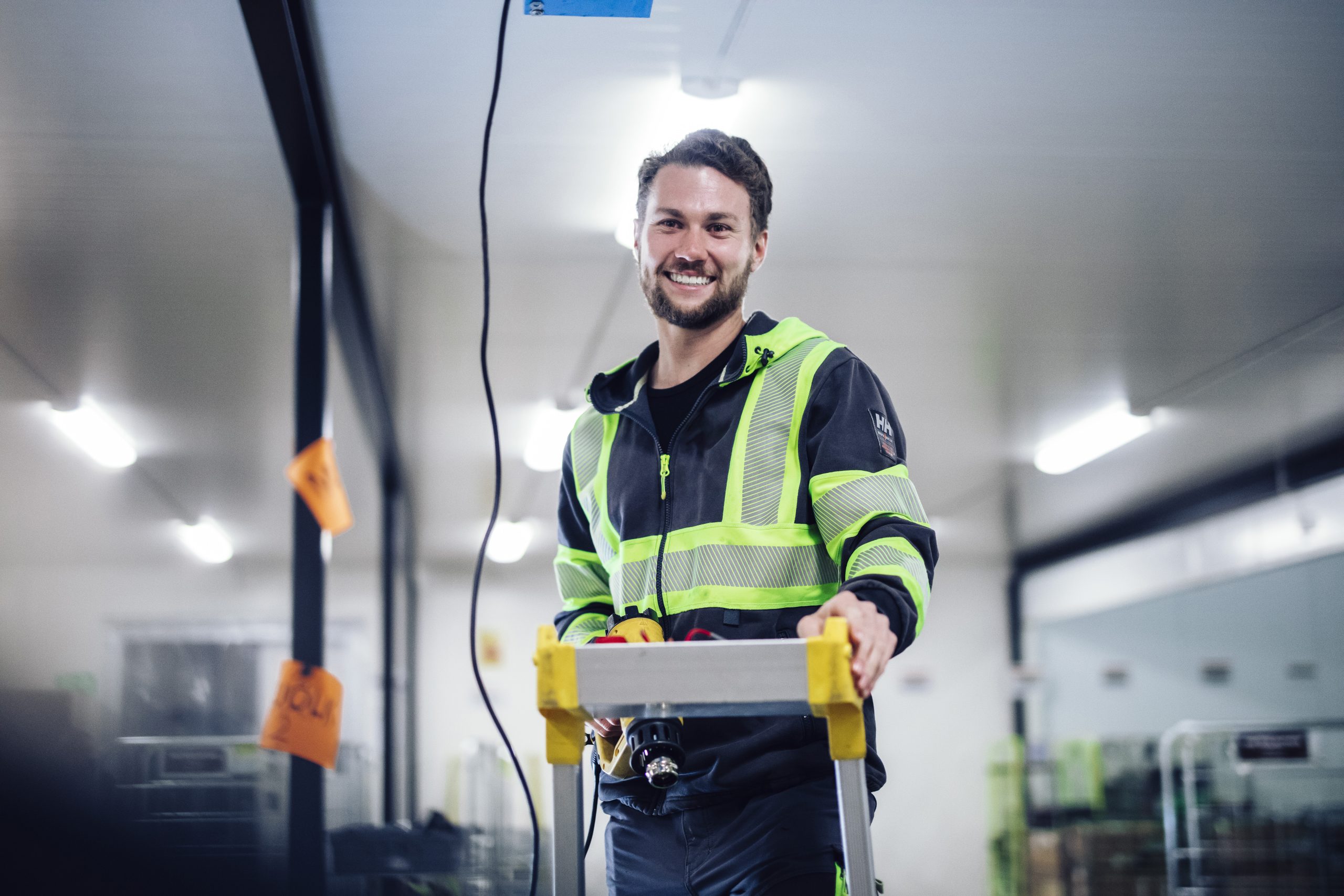 En man som står på en stege och ler till kameran