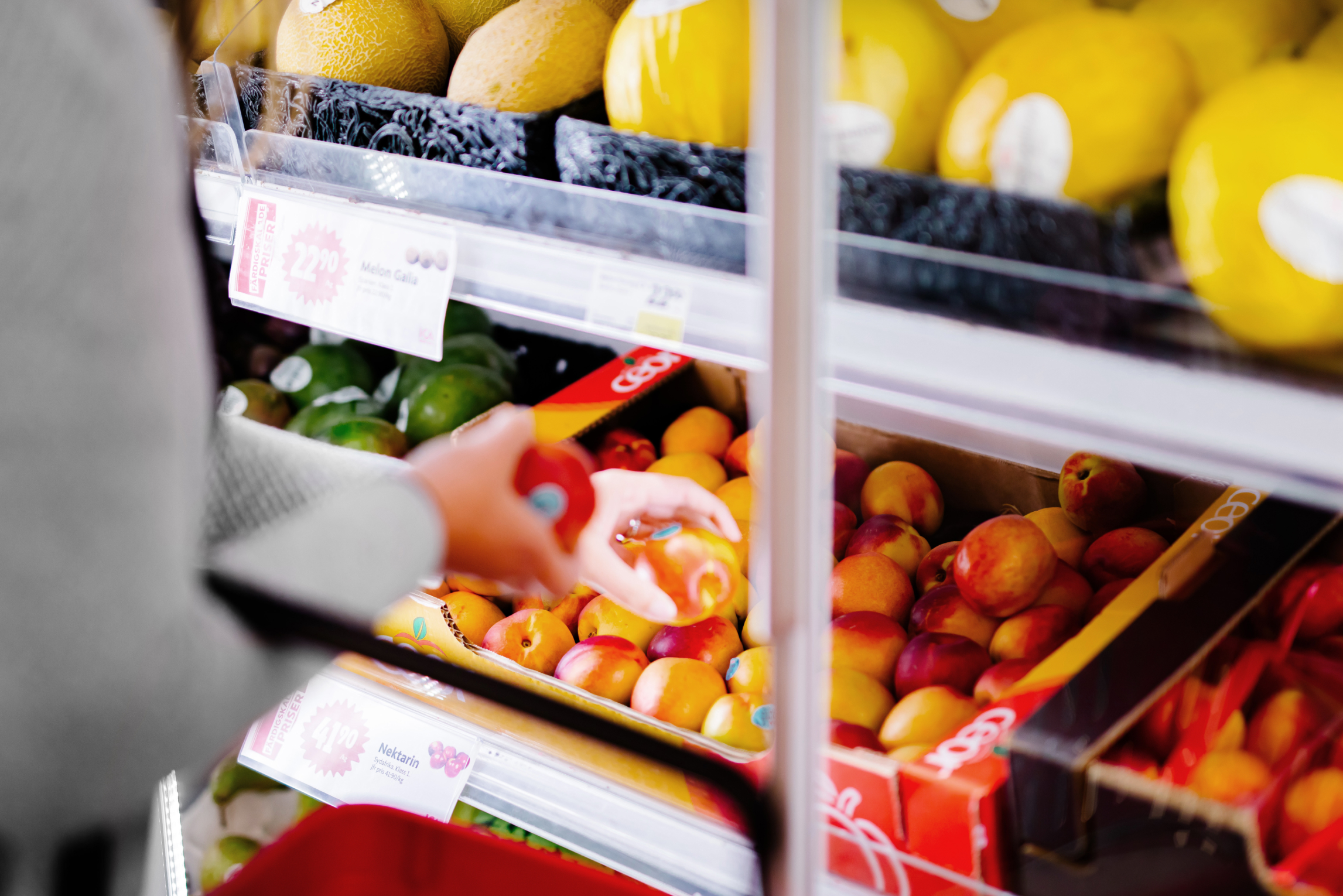 En person som sträcker sig efter en frukt i en butik