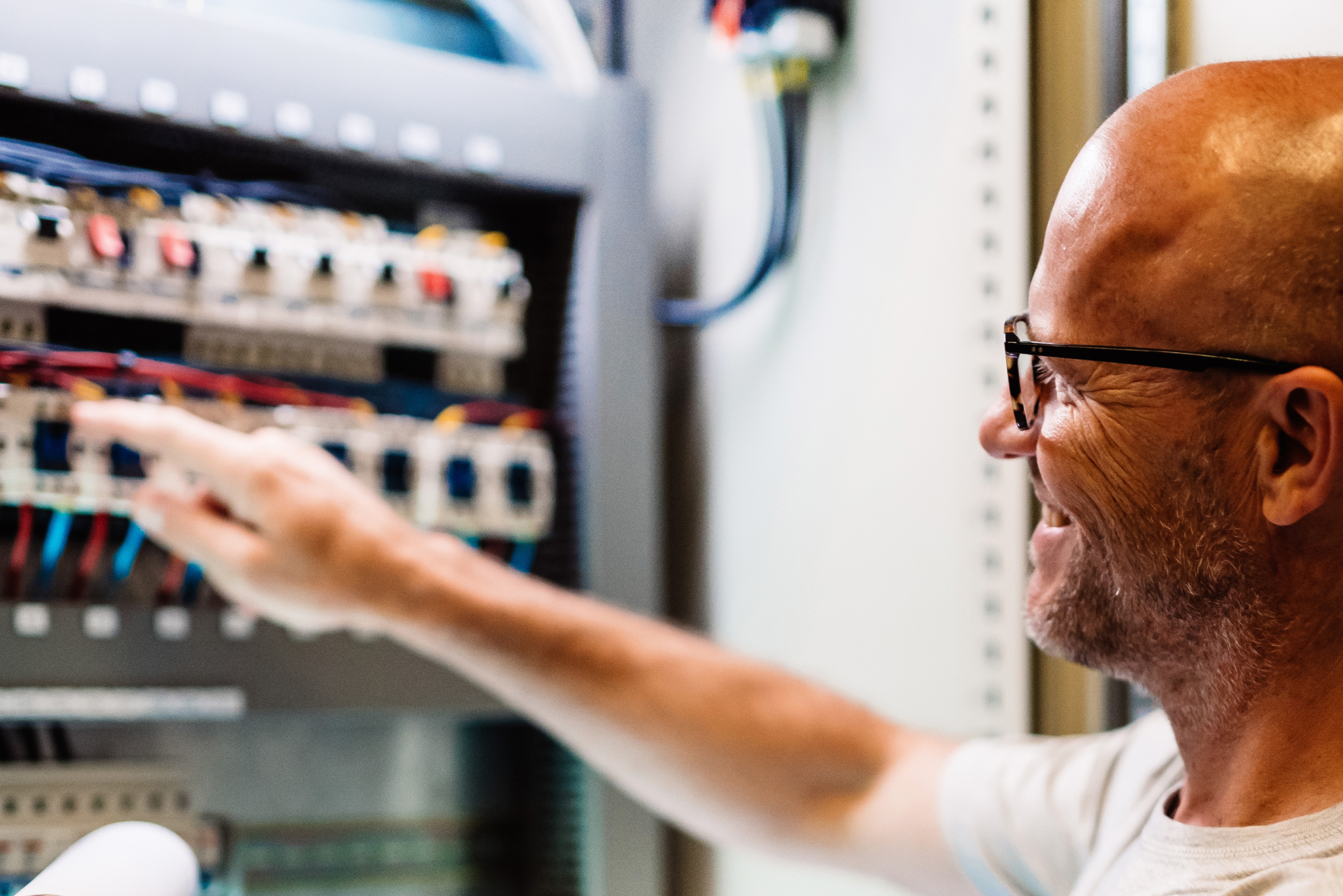 En man som ler och sträcker sig mot en elcentral