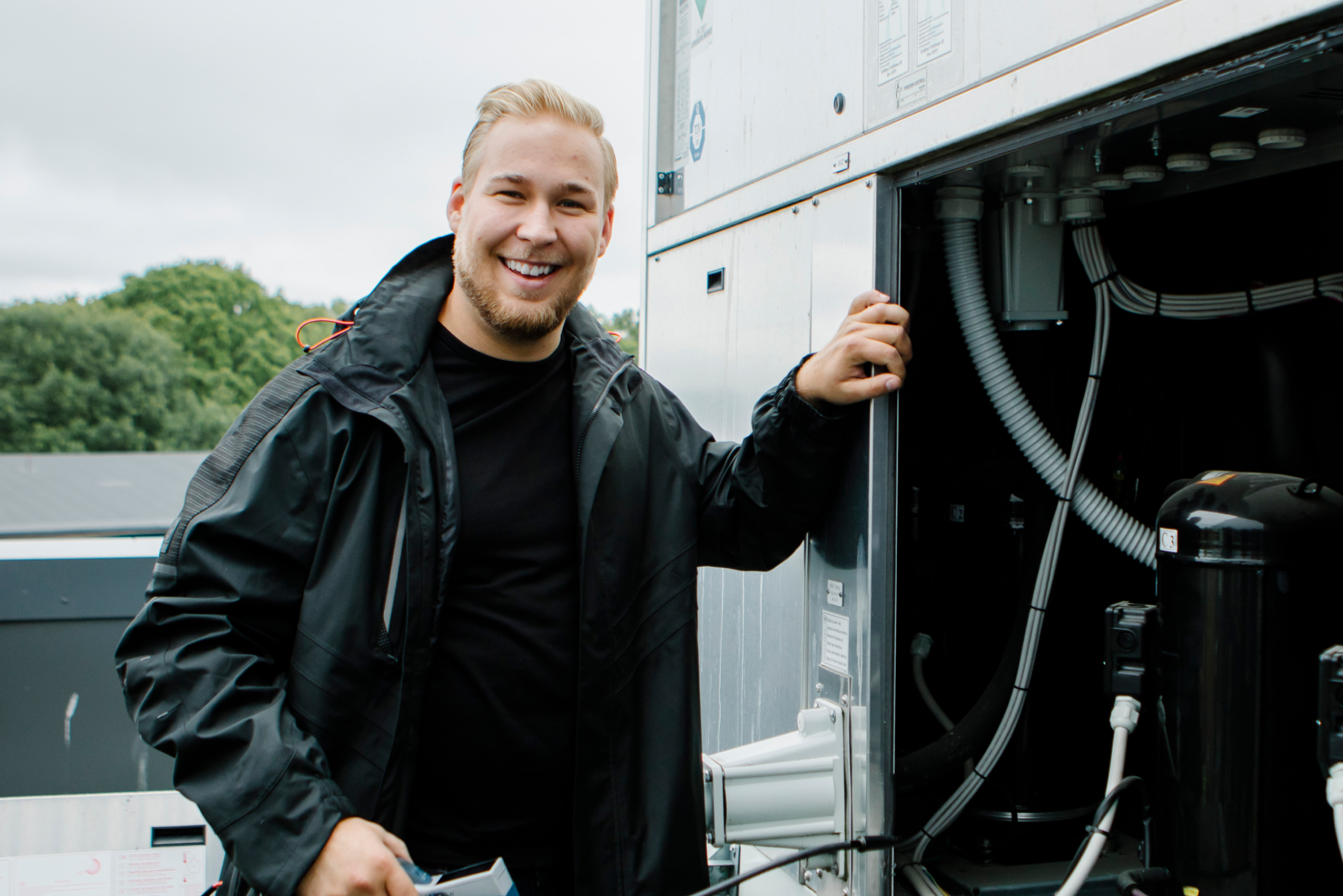 En man som lutar sig mot en servicebil och ler