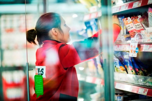 Personal i en matvarubutik som organiserar kylhyllorna